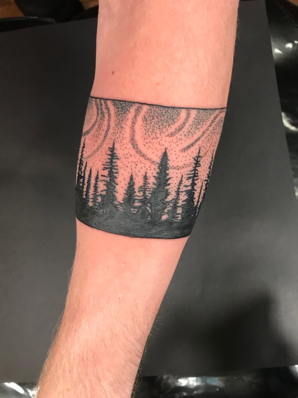 Blackwork tattoo forest treeline with dotwork swirls armband on forearm in Los Angeles