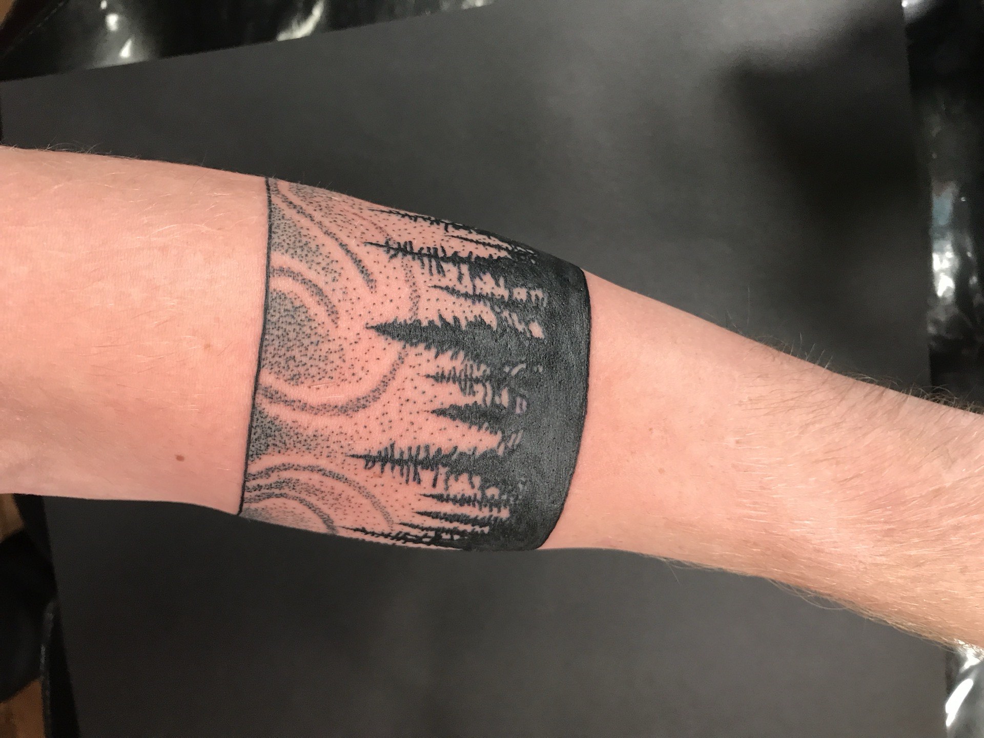 Blackwork tattoo forest treeline with dotwork swirls armband on forearm in Los Angeles