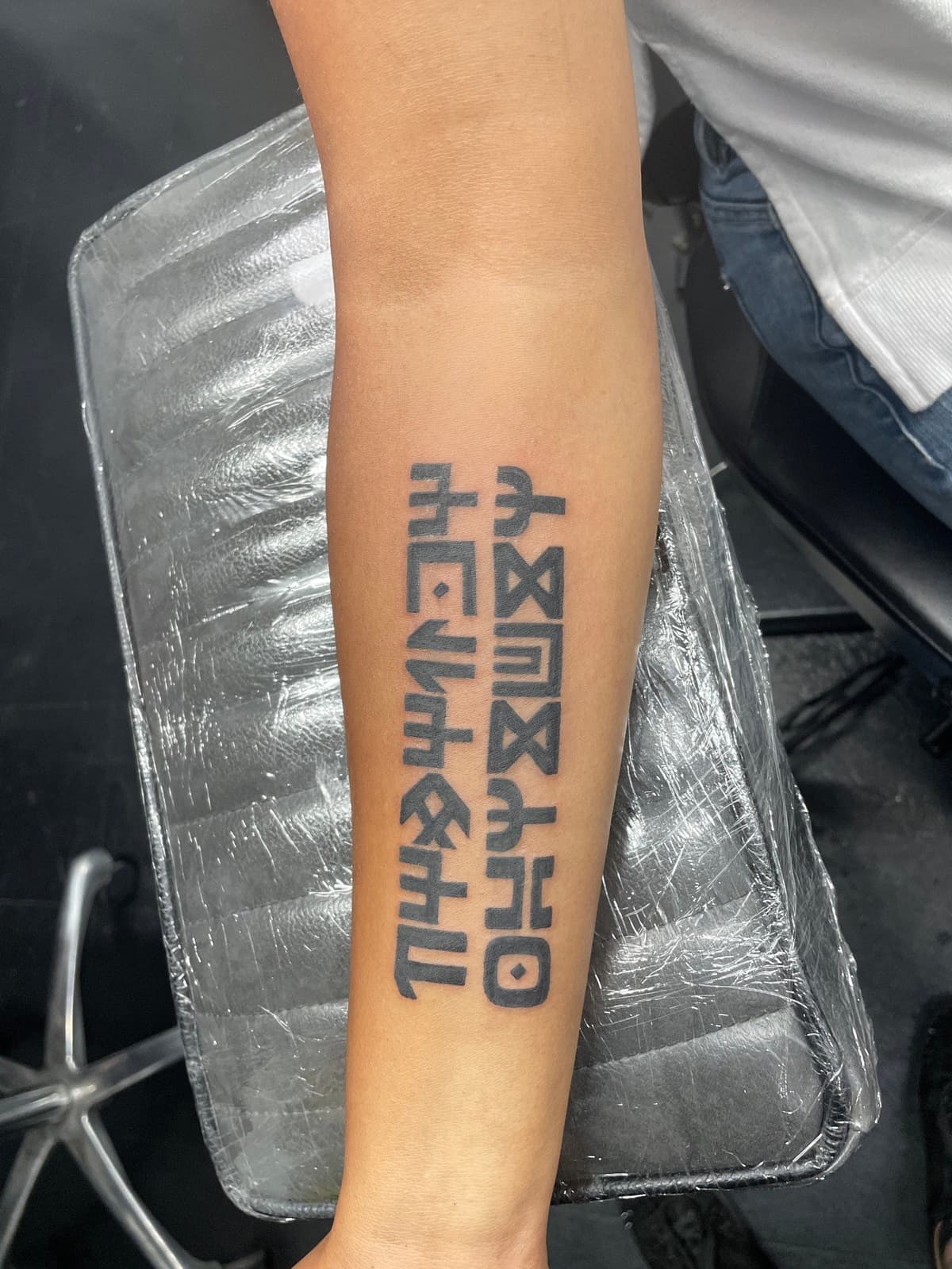 Blackwork tattoo bold Ethiopic script on forearm in Los Angeles