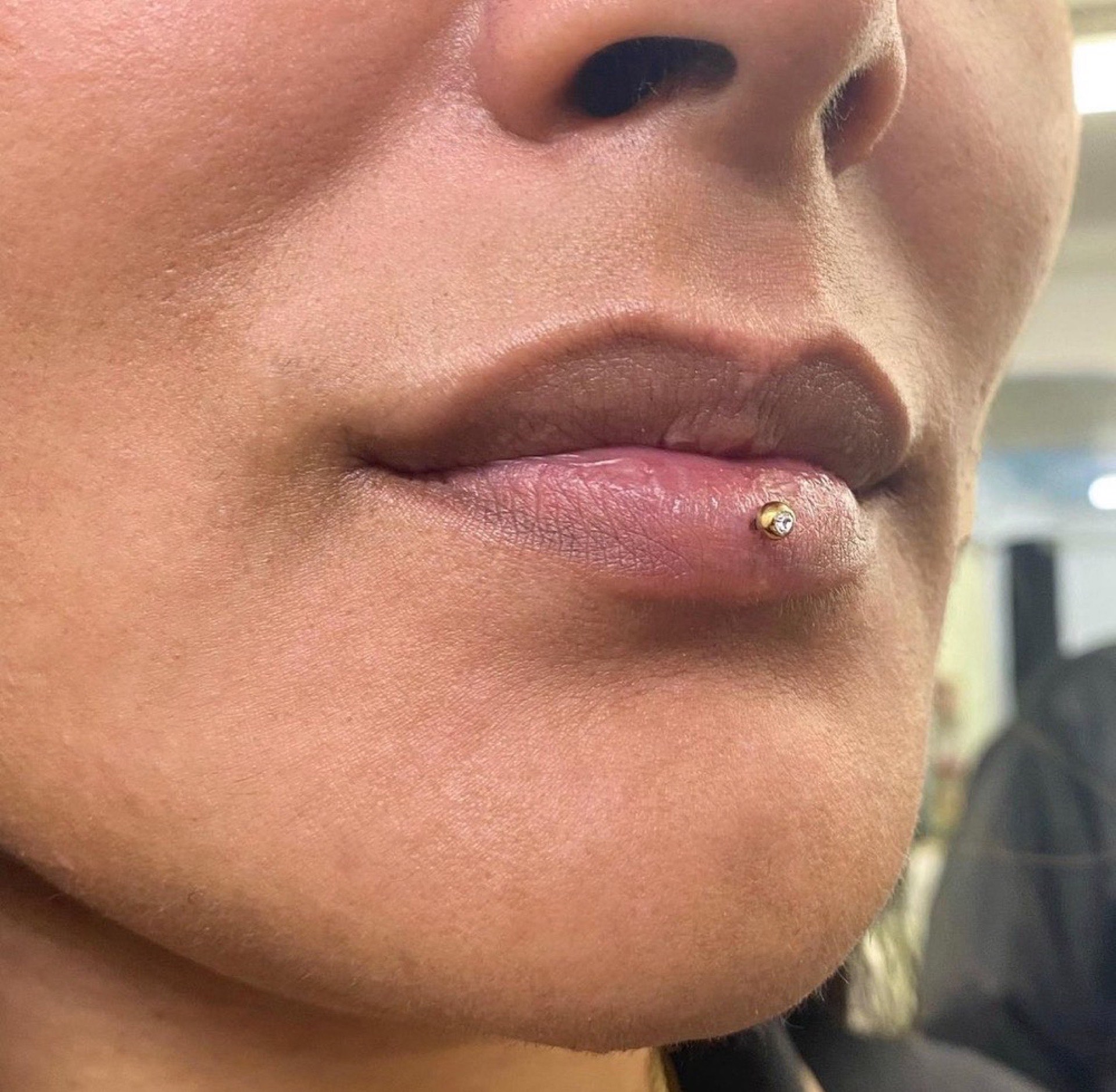 Lip piercing with large captive bead ring paired with double eyebrow piercings and nostril stud at Apollo Studio