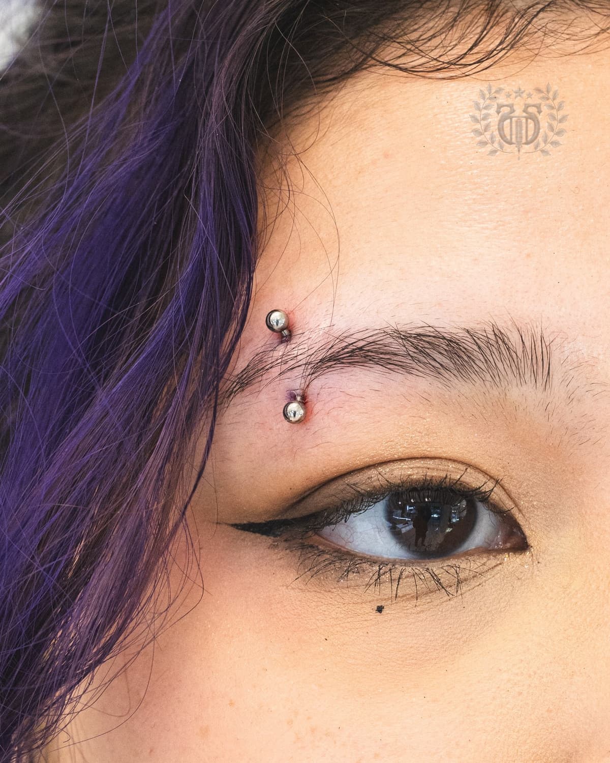 Silver ball curved barbell eyebrow piercing close-up at Apollo Studio