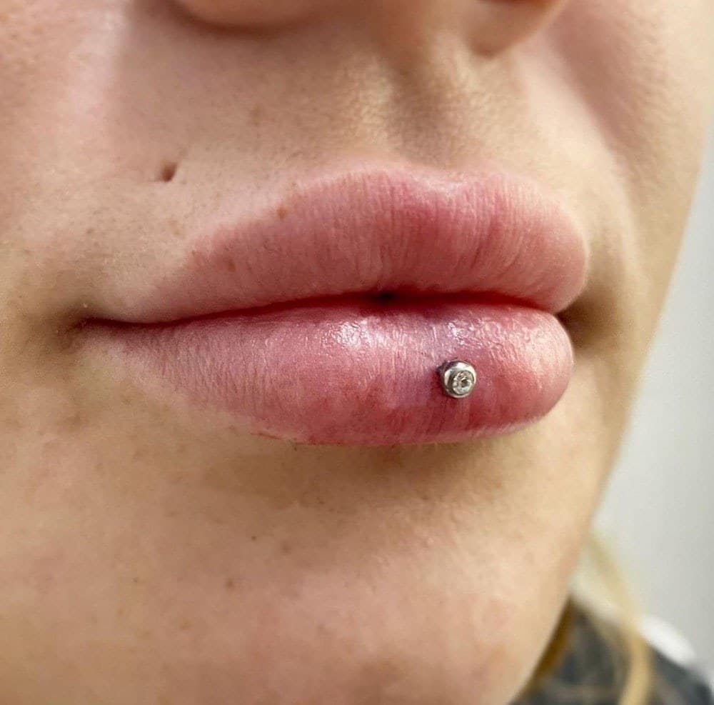 Center labret piercing with silver CZ bezel stud close-up at Apollo Studio